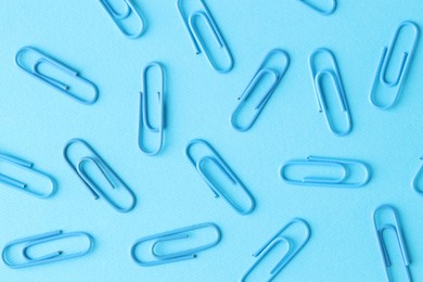 Photo of Many paper clips on light blue background, flat lay