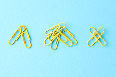 Many paper clips on light blue background, flat lay