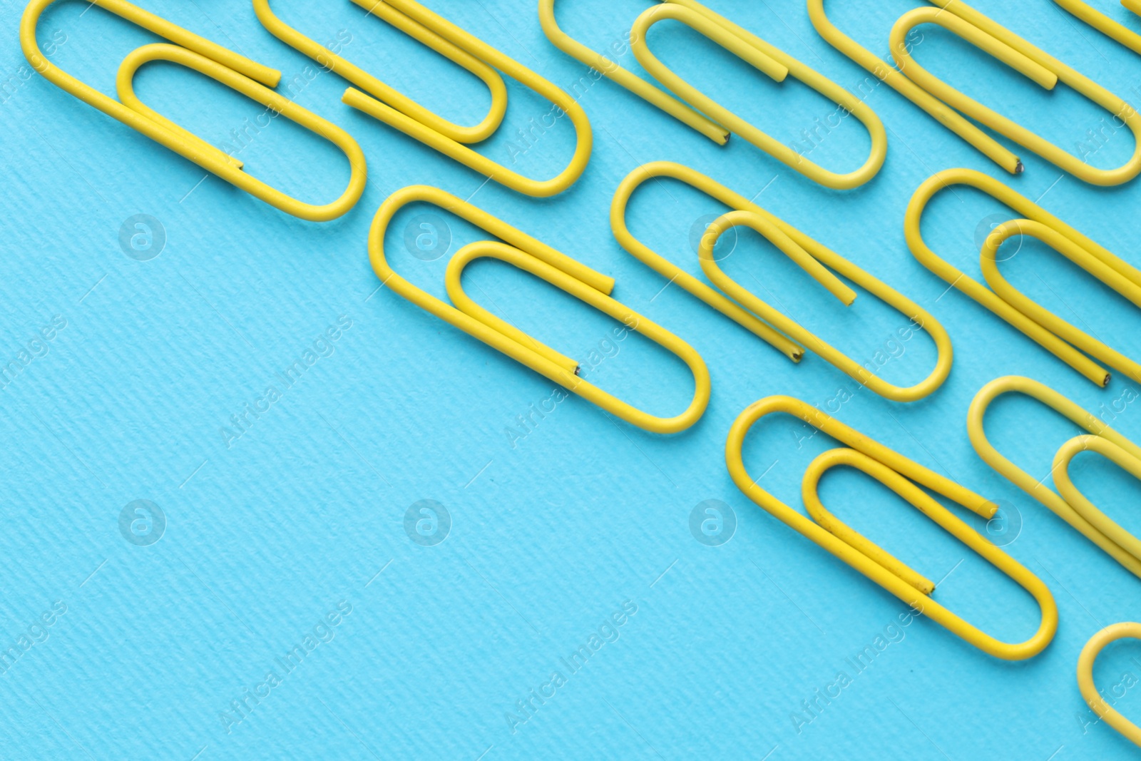 Photo of Many paper clips on light blue background, flat lay. Space for text