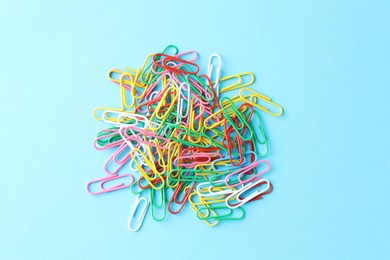 Photo of Colorful paper clips on light blue background, top view