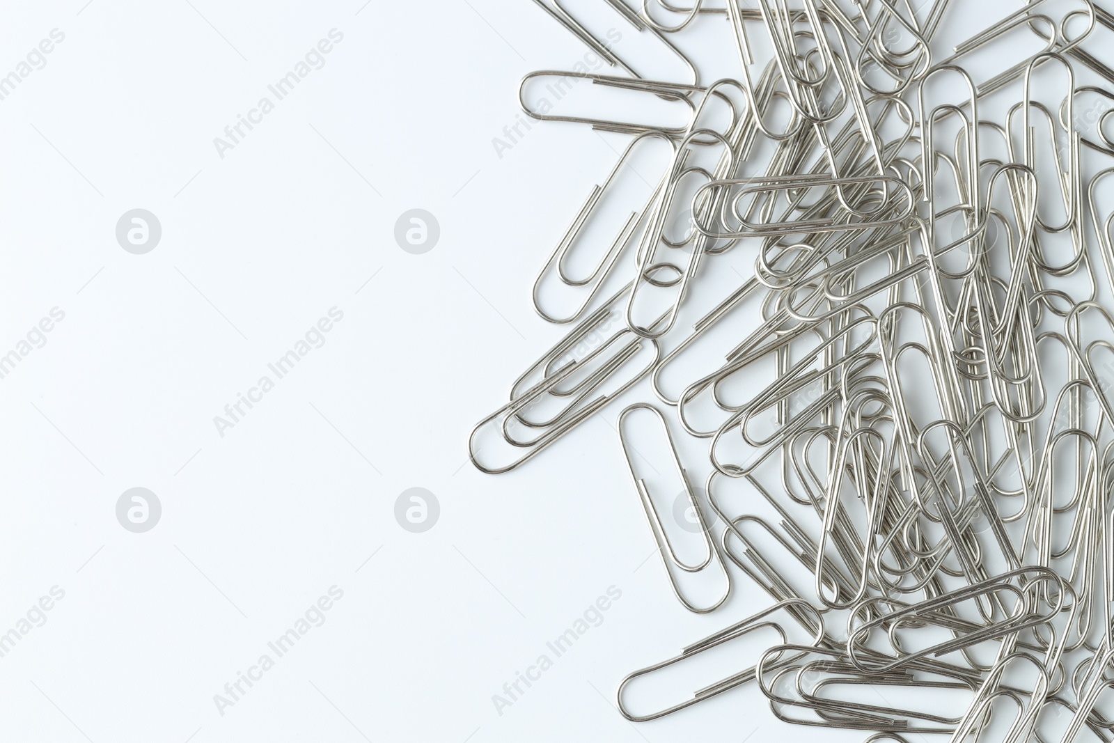 Photo of Metal paper clips on light background, top view. Space for text