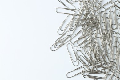 Metal paper clips on light background, top view. Space for text