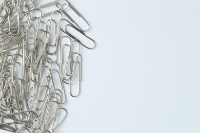 Photo of Metal paper clips on light background, top view. Space for text