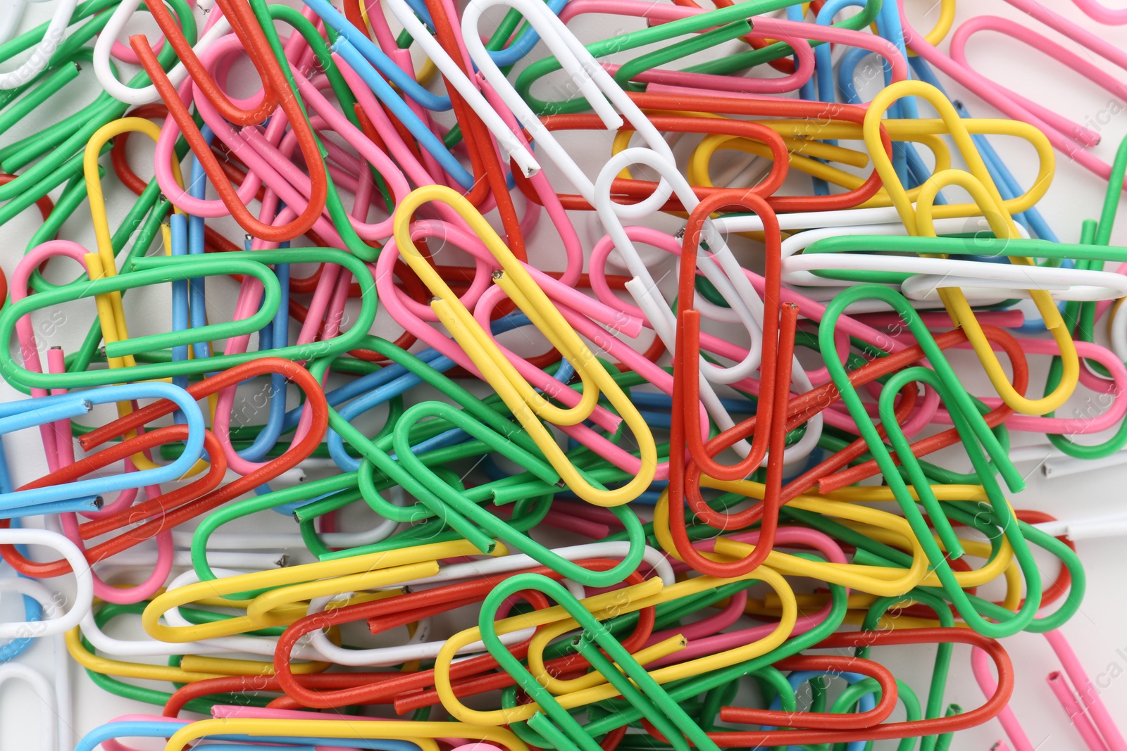 Photo of Colorful paper clips on light background, top view