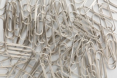 Photo of Metal paper clips on light background, top view