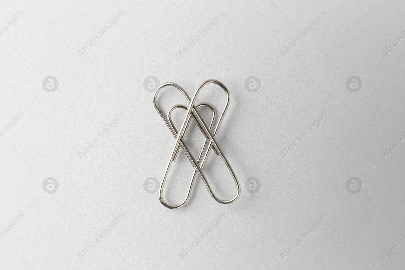 Photo of Metal paper clips on light background, top view