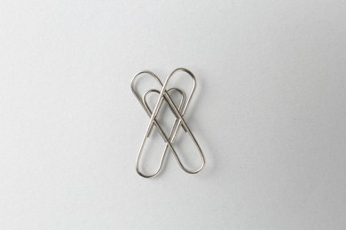 Photo of Metal paper clips on light background, top view