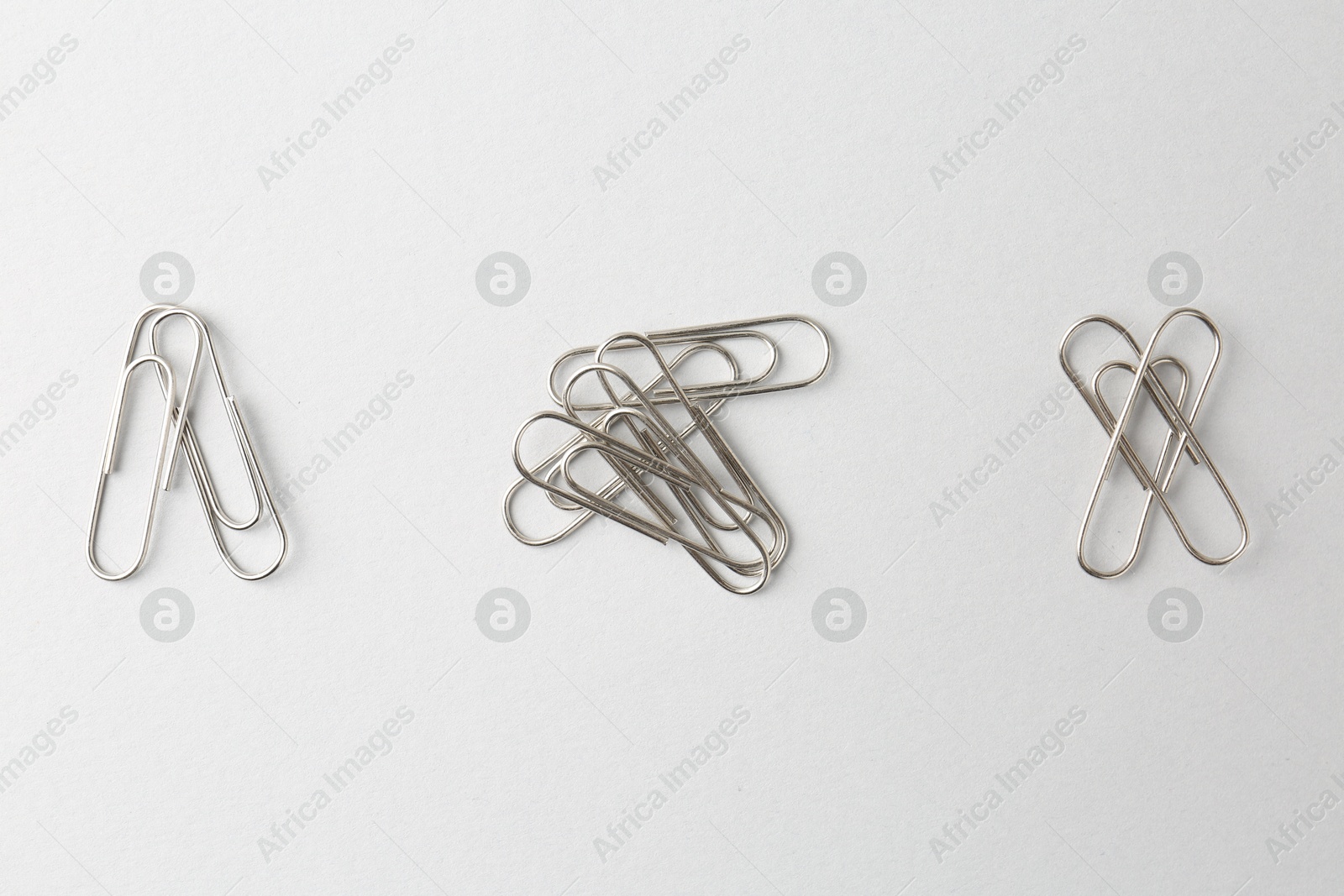 Photo of Metal paper clips on light background, flat lay