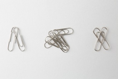 Photo of Metal paper clips on light background, flat lay