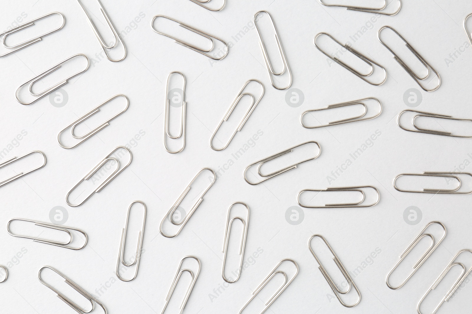 Photo of Metal paper clips on light background, flat lay