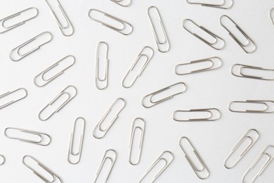 Metal paper clips on light background, flat lay