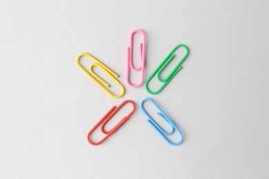 Photo of Colorful paper clips on light background, flat lay