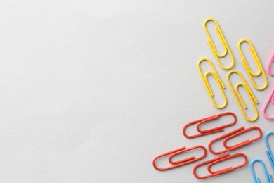 Photo of Colorful paper clips on light background, flat lay. Space for text