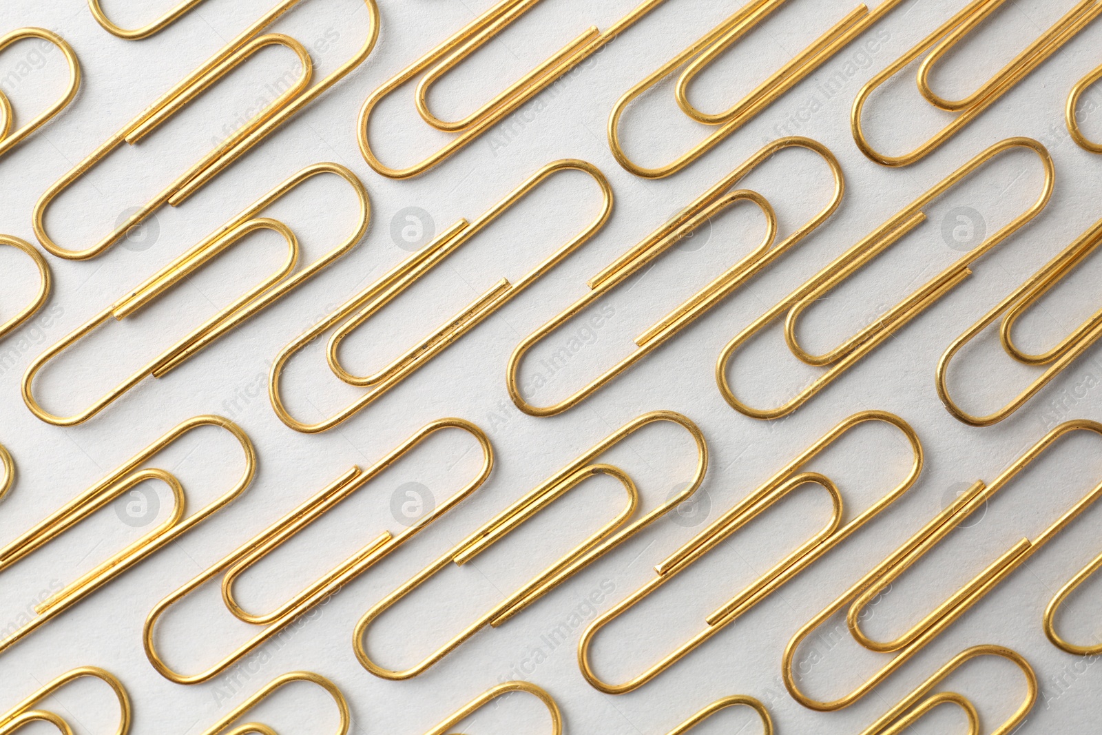 Photo of Golden paper clips on light background, flat lay