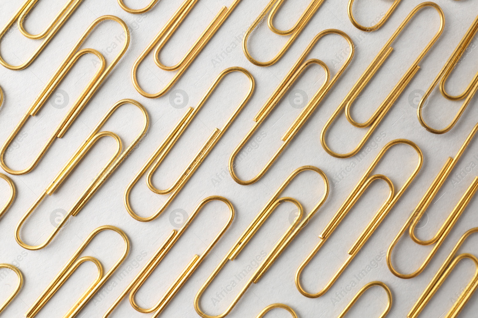 Photo of Golden paper clips on light background, flat lay