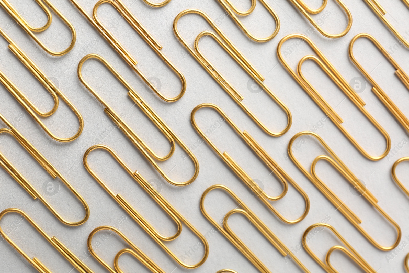 Photo of Golden paper clips on light background, flat lay