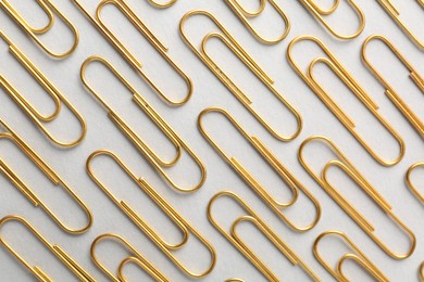 Photo of Golden paper clips on light background, flat lay