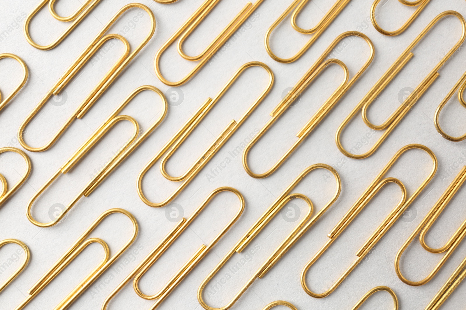 Photo of Golden paper clips on light background, flat lay