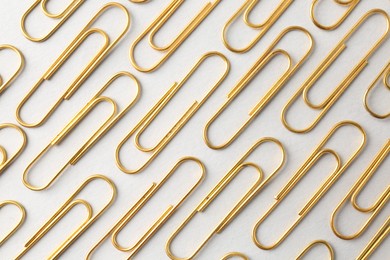 Photo of Golden paper clips on light background, flat lay