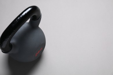 Photo of One kettlebell on light grey background. Space for text