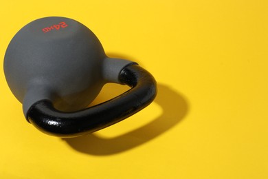 Photo of One kettlebell on yellow background, closeup. Sport equipment