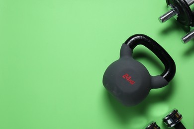 Photo of Kettlebell and dumbbells on green background, flat lay. Space for text