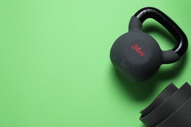 Photo of Kettlebell and mat on green background, top view. Space for text