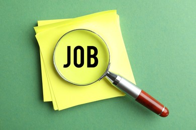 Image of Job search concept. Paper note with word on green background, view through magnifying glass