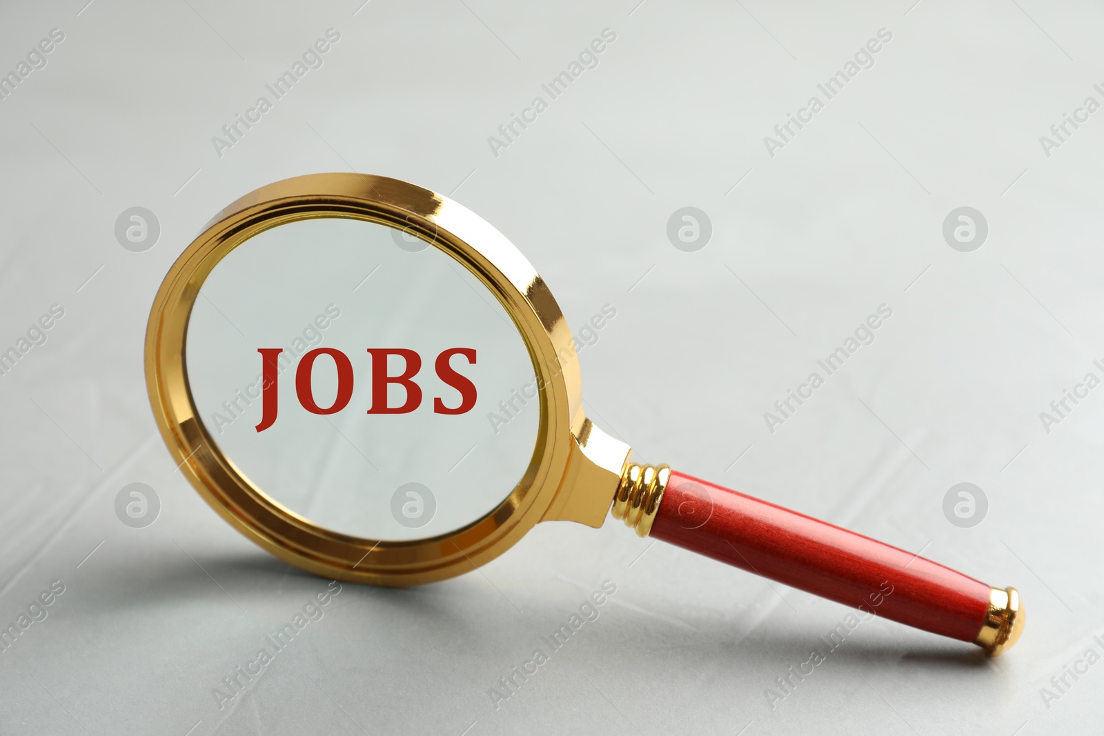 Image of Job search concept. Word on light grey background, view through magnifying glass