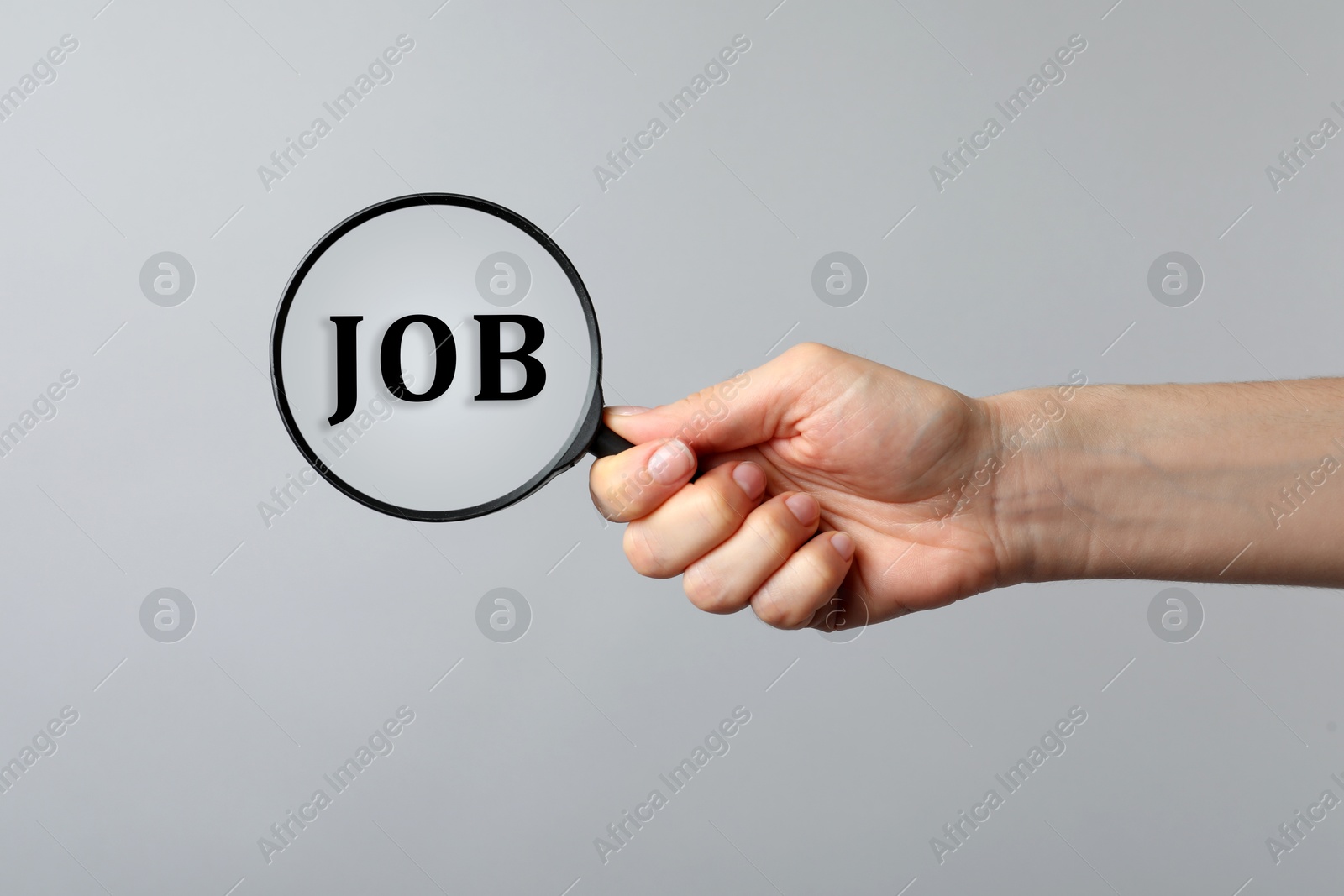 Image of Job search concept. Woman looking at word through magnifying glass on grey background, closeup