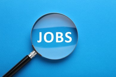 Image of Job search concept. Word on blue background, view through magnifying glass