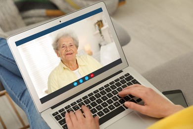 Grandmother and granddaughter talking via video call on laptop. Woman using computer at home, closeup