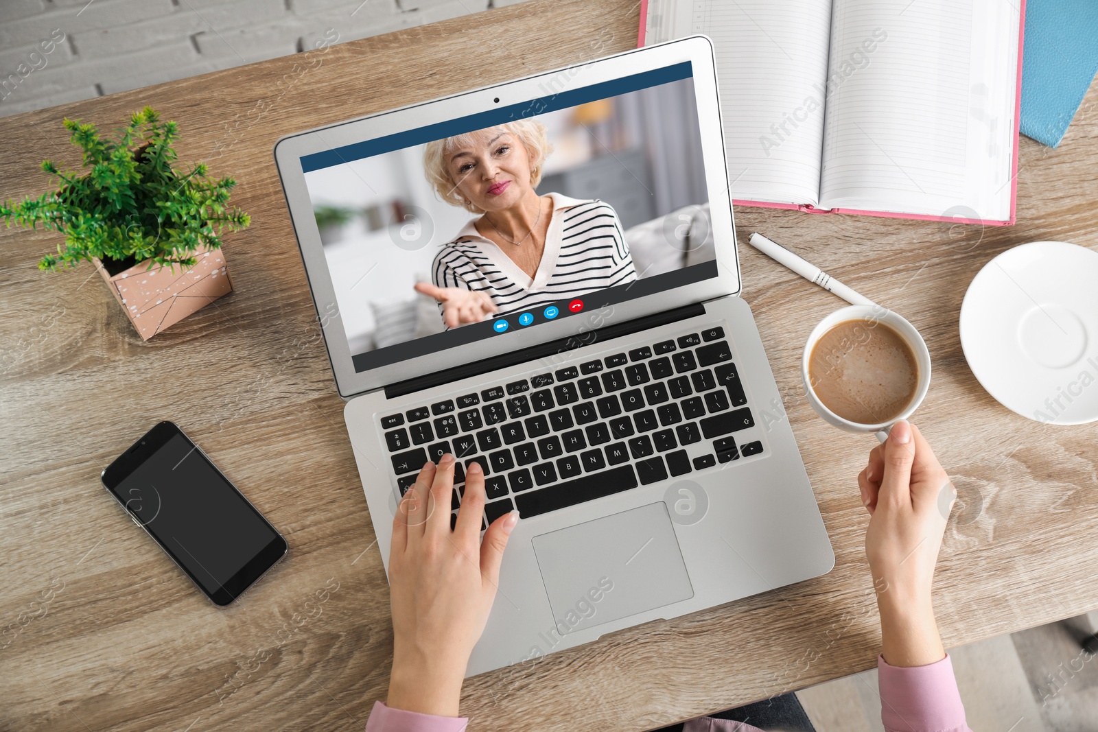 Image of Grandmother and granddaughter talking via video call on laptop. Woman using computer at table, top view