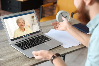 Grandmother and grandson talking via video call on laptop. Man using computer at home, closeup