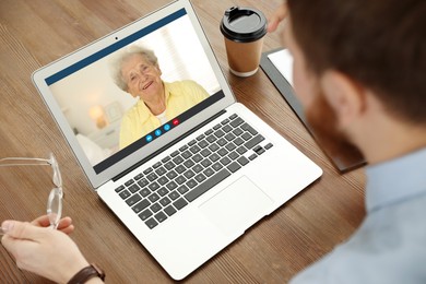 Grandmother and grandson talking via video call on laptop. Man using computer at table