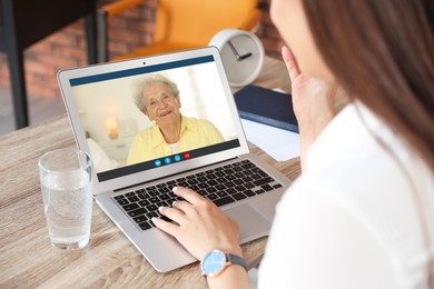 Grandmother and granddaughter talking via video call on laptop. Woman using computer at home, closeup