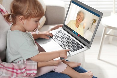 Grandmother and her daughter with granddaughter talking via video call on laptop. Woman with child using computer at home