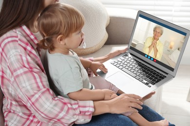 Image of Grandmother and her daughter with granddaughter talking via video call on laptop. Woman with child using computer at home