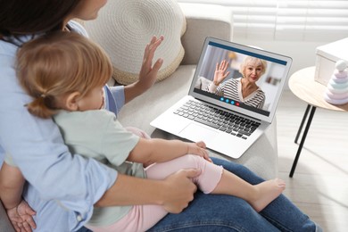 Image of Grandmother and her daughter with granddaughter talking via video call on laptop. Woman with child using computer at home