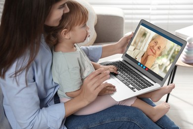 Image of Grandmother and her daughter with granddaughter talking via video call on laptop. Woman with child using computer at home