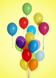 Image of Many colorful balloons in air on light yellowish green background. Birthday or other party decoration