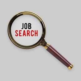 Image of Job search words on light grey background, view through magnifying glass