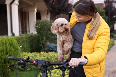 Photo of Woman with bicycle and cute Toy Poodle dog outdoors