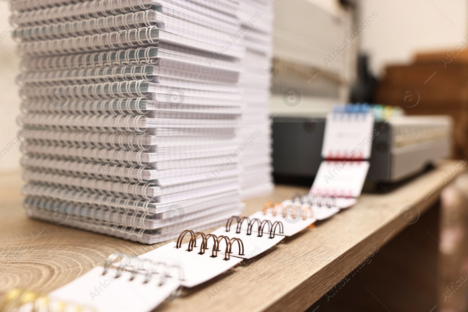 Photo of Stacks of notebooks and double loop wire binding spines on wooden table indoors, closeup