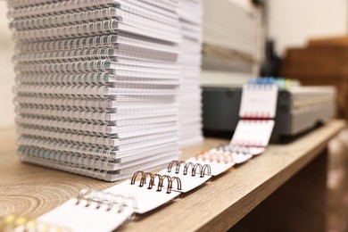 Photo of Stacks of notebooks and double loop wire binding spines on wooden table indoors, closeup