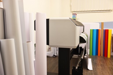 Photo of Wide-format printer and paper rolls indoors. Printing house