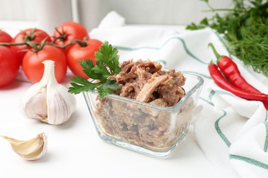 Photo of Canned meat with parsley in bowl and fresh vegetables on white wooden table