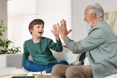 Photo of Grandpa and his grandson giving five on sofa at home