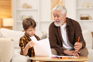 Photo of Grandpa and his grandson drawing at table indoors