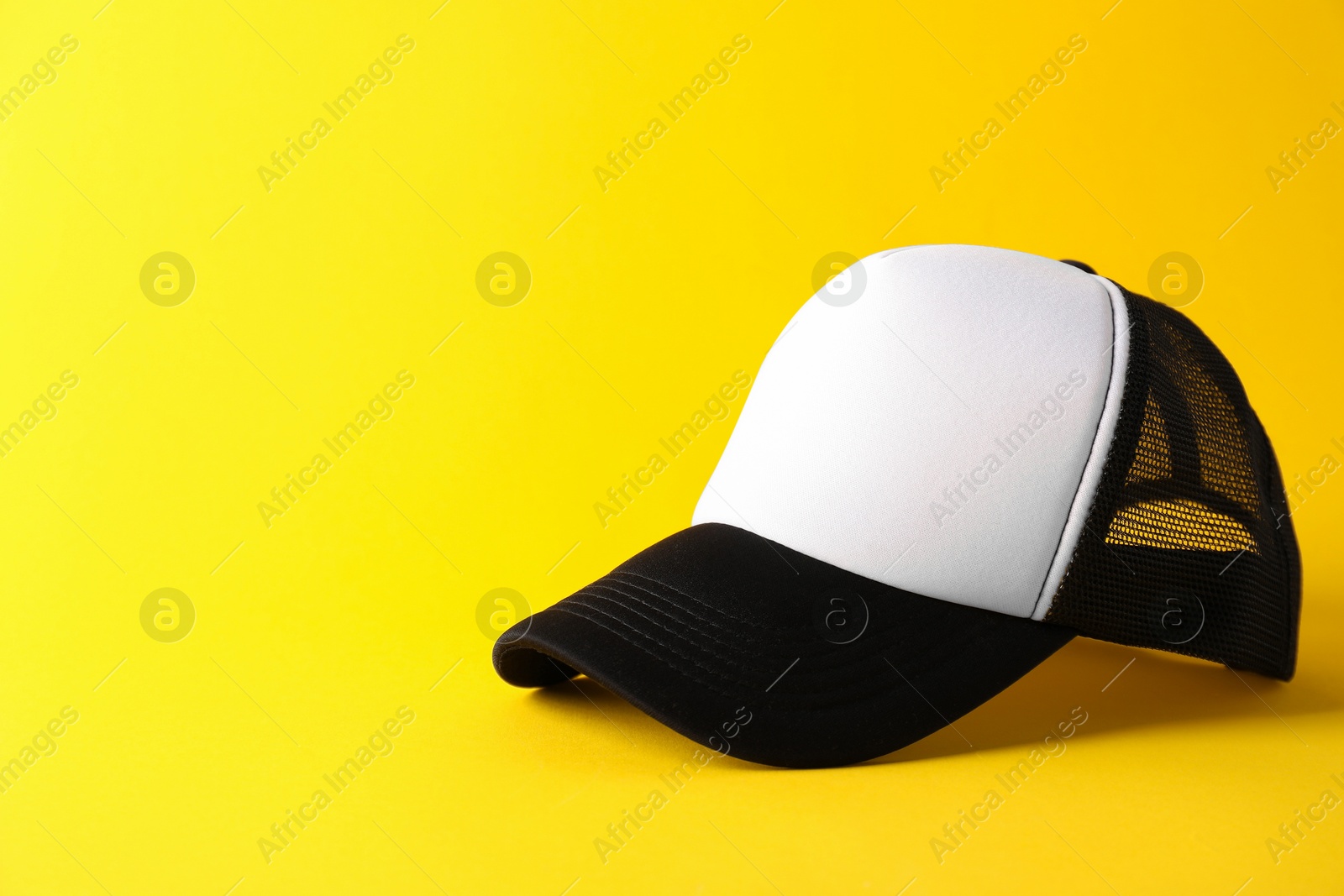 Photo of Stylish baseball cap on yellow background. Mockup for design